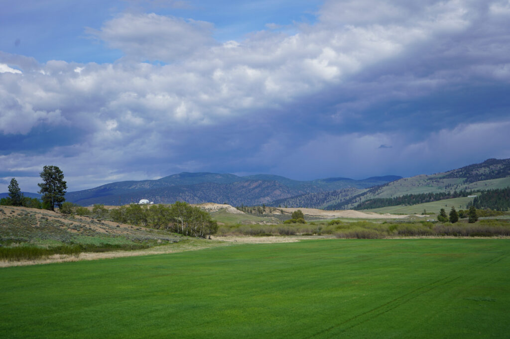 View of Merit, mountain, green grass, and sandy hills.